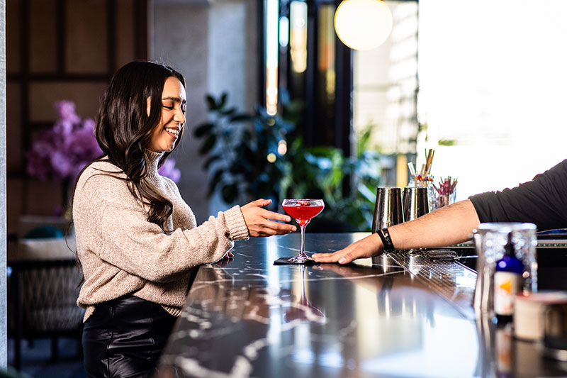 woman grabbing cocktail at High Praise